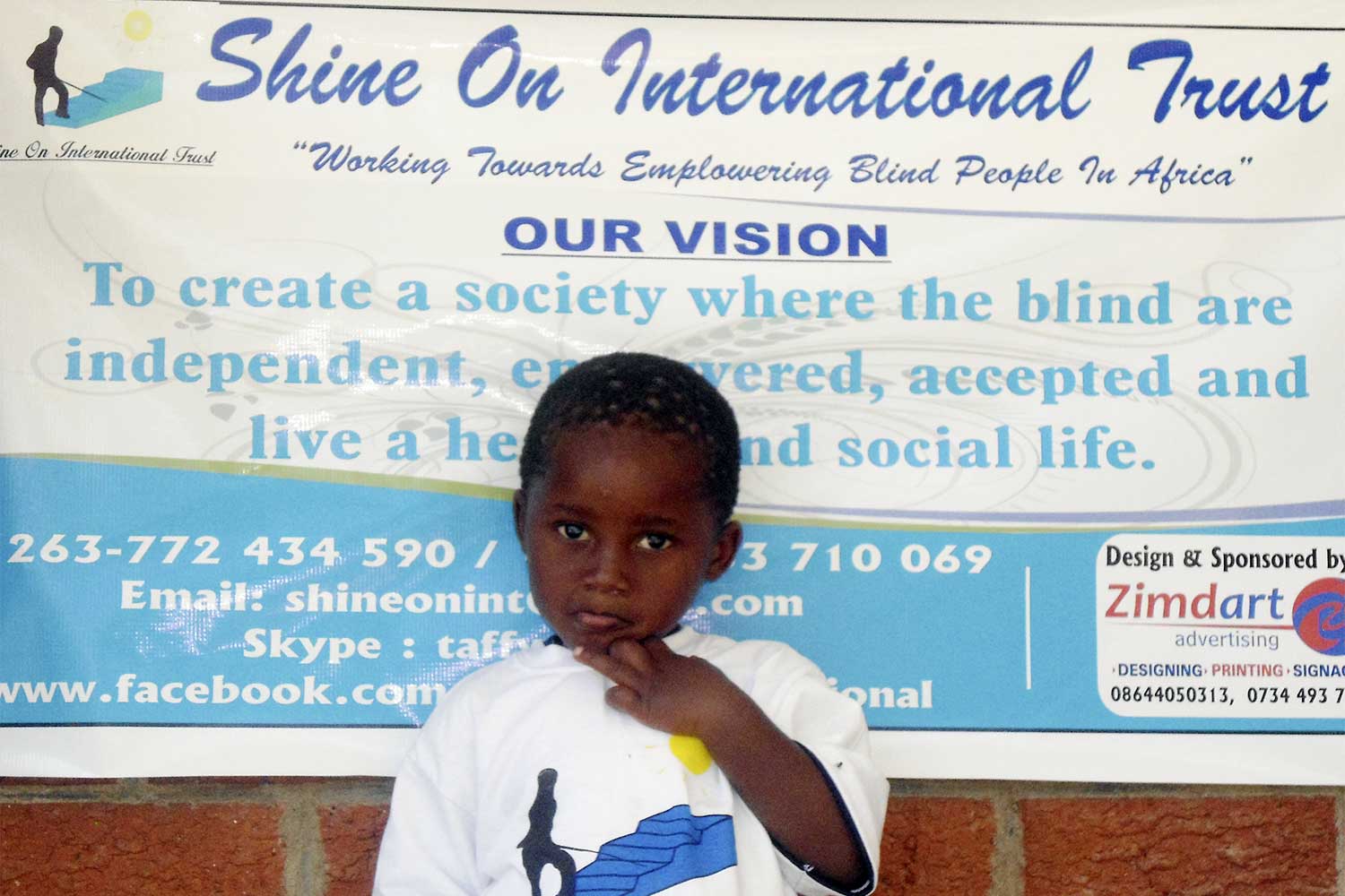 Boy in front of Shine on International Trust poster
